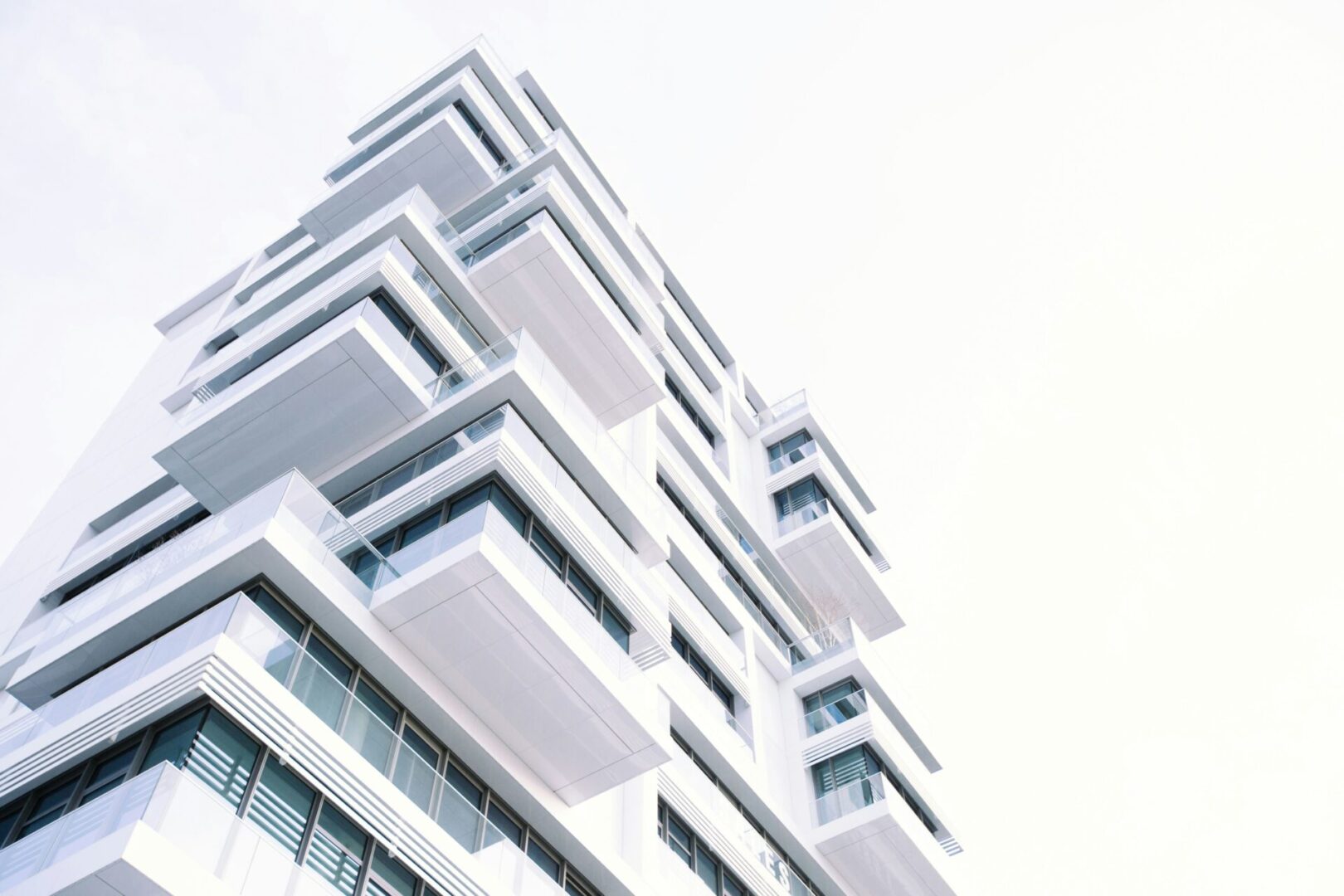 A tall white building with many windows on the outside.